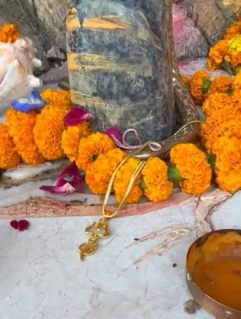 A gold-plated trishul pendant with a chain
