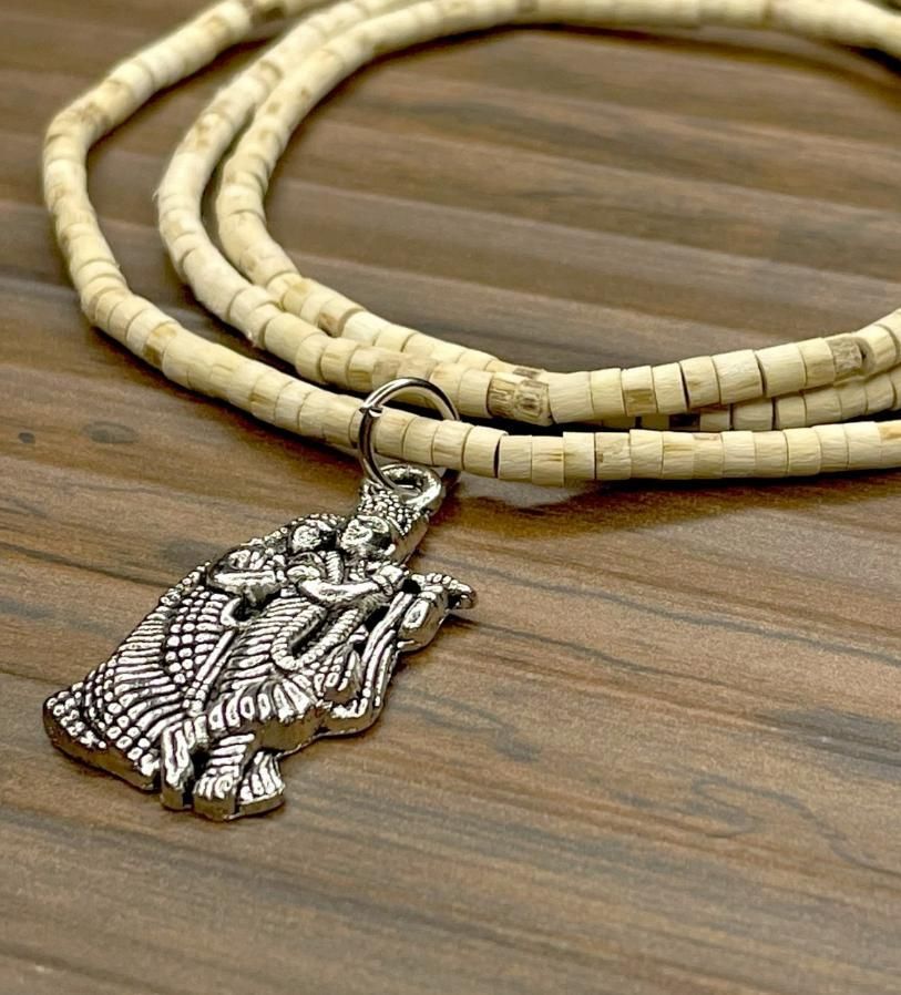 Two wooden Tulsi Mala necklaces with pendants, one depicting a bird and the other a geometric pattern, displayed against a wooden background.