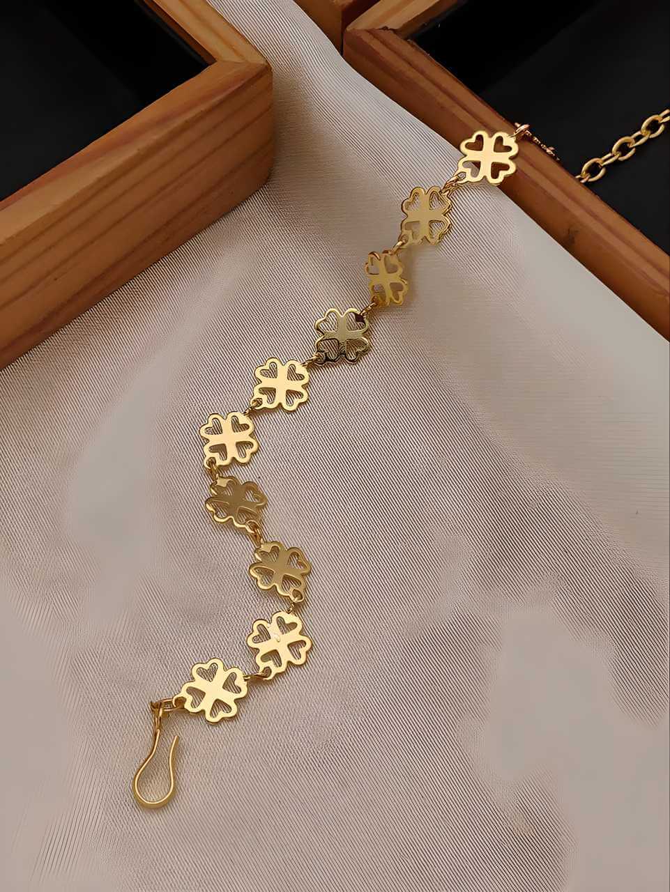 Gold floral bracelet on a beige fabric background