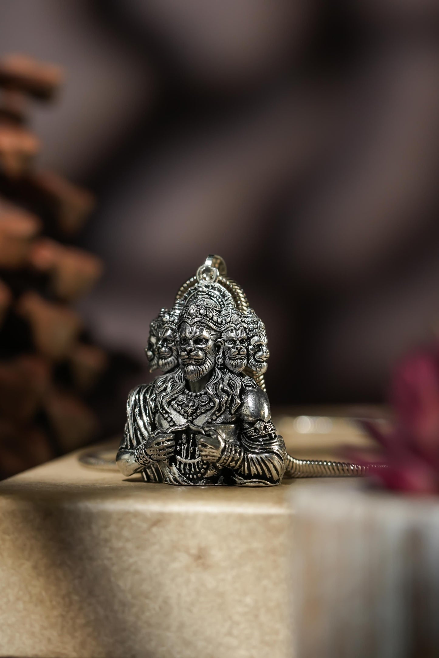 A silver-colored Panchamukhi Hanuman pendant attached to a snake chain