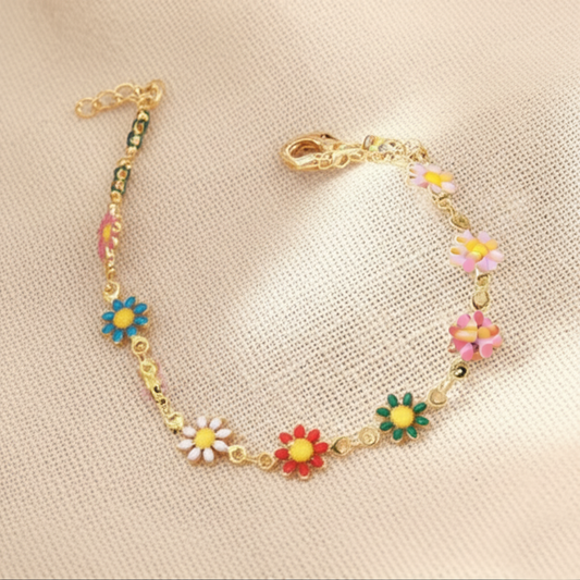Gold bracelet with colorful flower charms on a beige surface