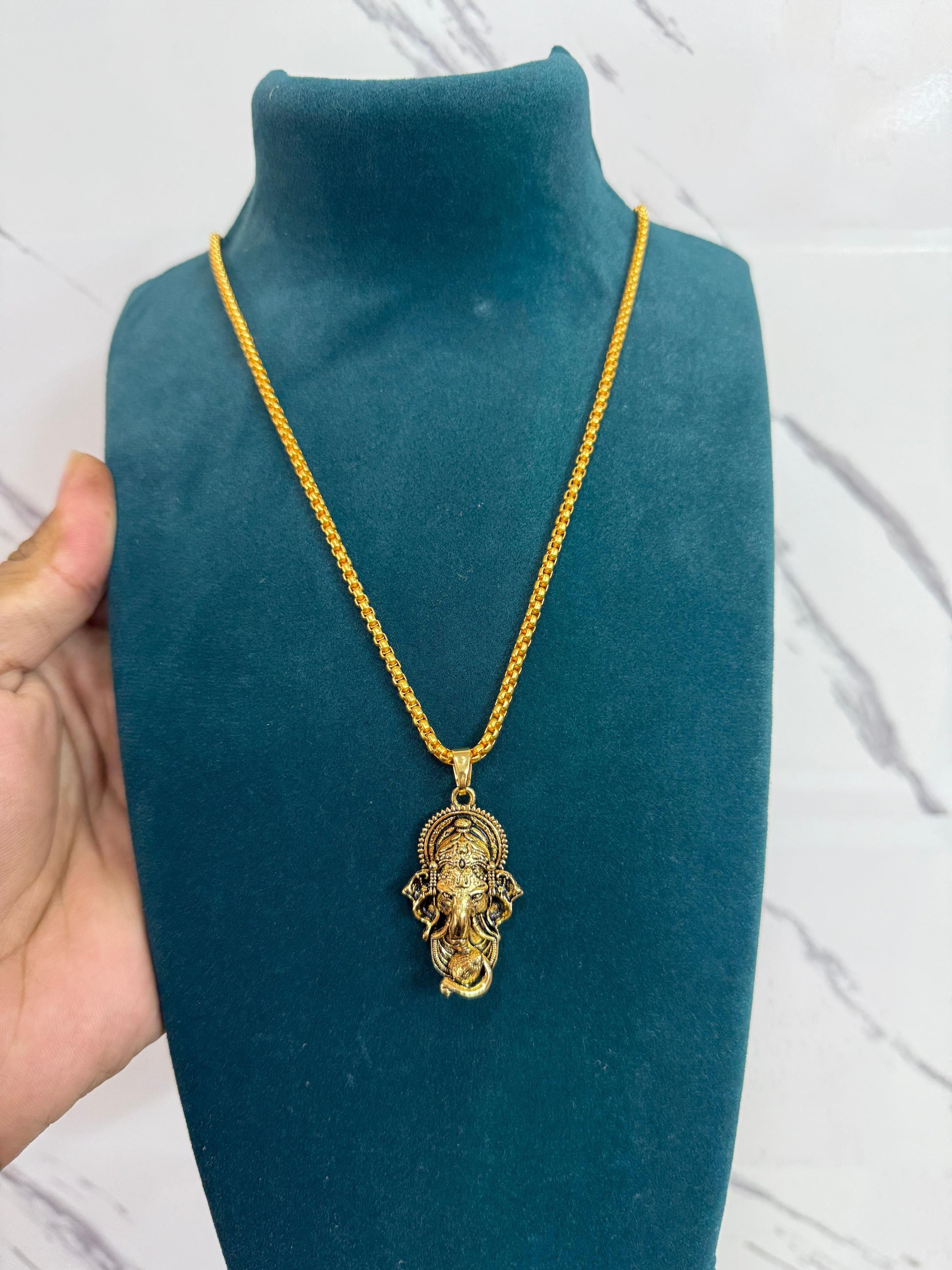 A gold-colored Ganesha pendant attached to a snake chain