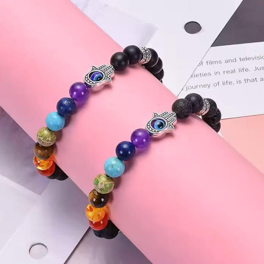 A multicolored beaded bracelet with a black lava stone base and a silver-colored hamsa hand charm