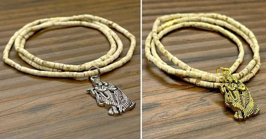 Two wooden Tulsi Mala necklaces with pendants, one depicting a bird and the other a geometric pattern, displayed against a wooden background.