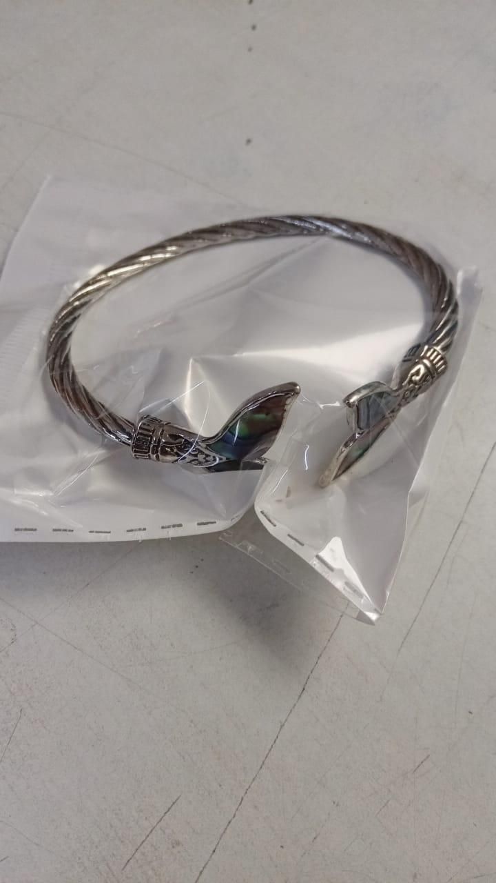 An abalone shell mermaid tail bangle bracelet displayed on a textured surface with a twisted metal band and inlayed shell details.