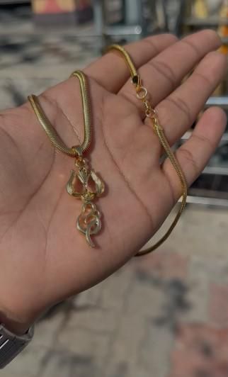 A gold-plated trishul pendant with a chain