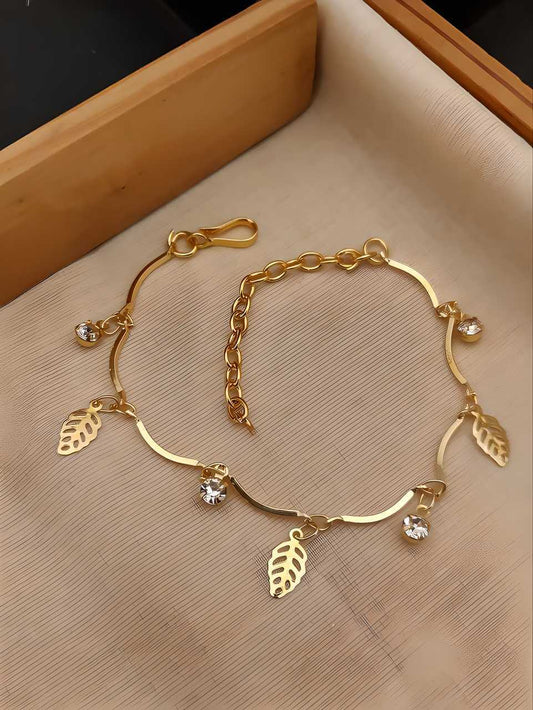 Gold bracelet with leaf charms on a beige surface