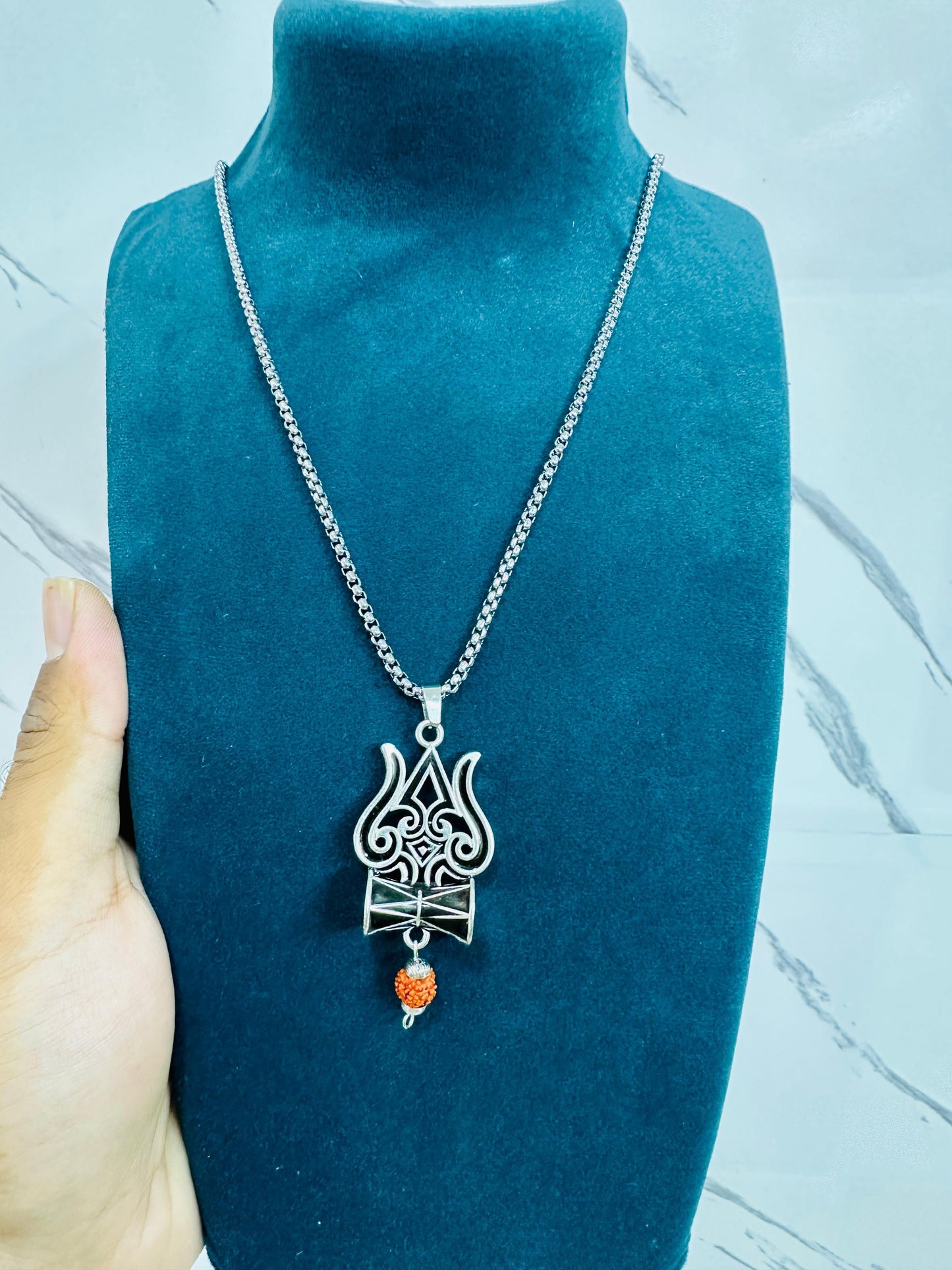 A silver oxidised Trishul Damru Rudraksha pendant chain with a small red bead on the pendant
