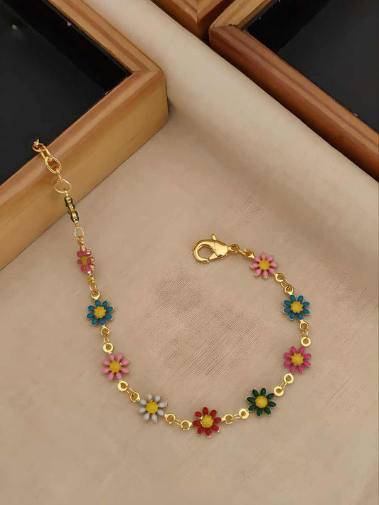 Gold bracelet with colorful flower charms on a beige surface