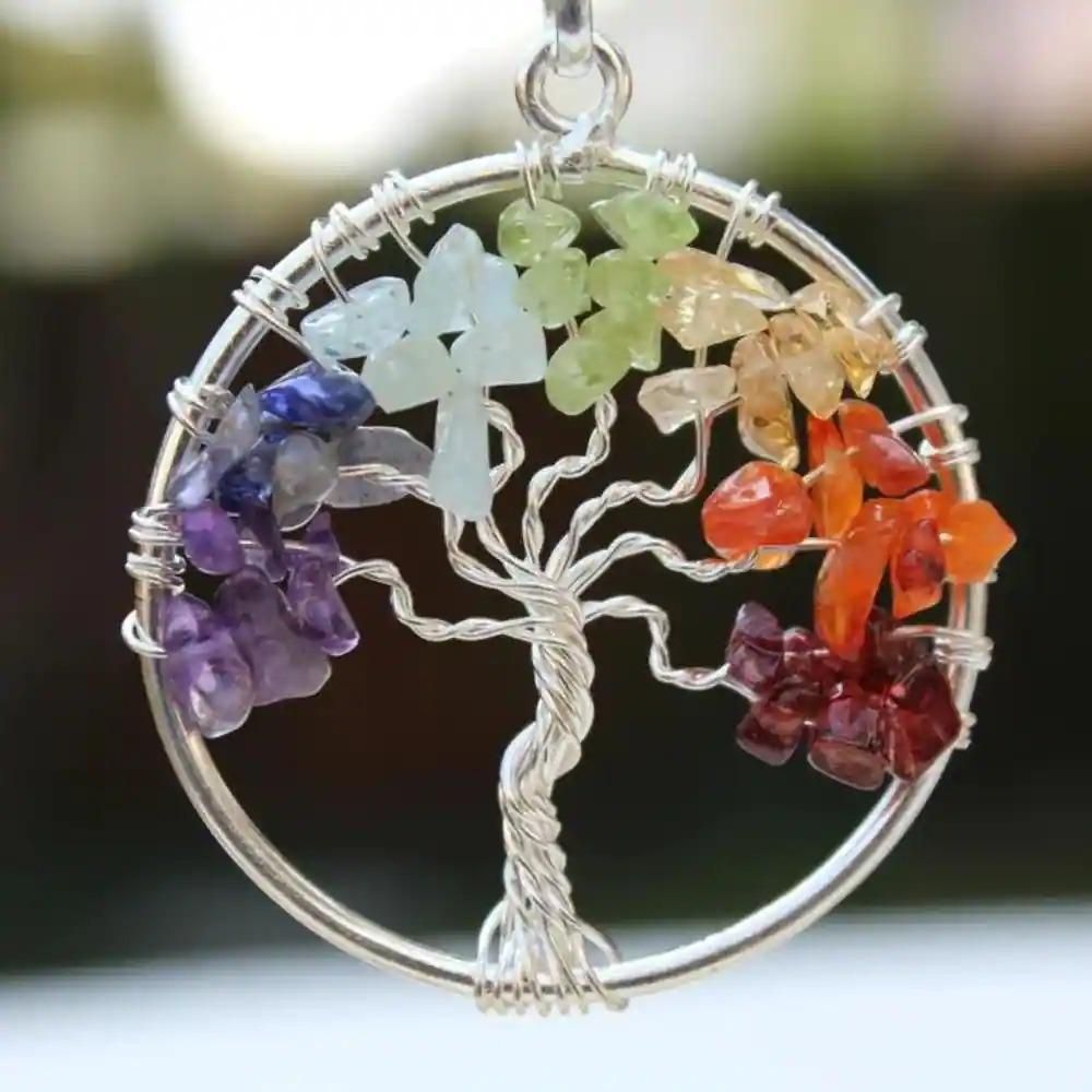 A silver-colored Tree of Life pendant with multicolored chakra stones arranged in a circle,