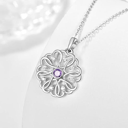 A silver birthstone pendant with a floral design, featuring a purple stone in the center, attached to a silver chain.