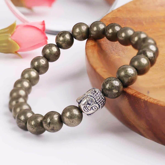 Bracelet with pyrite beads and a silver Buddha charm on a wooden surface.