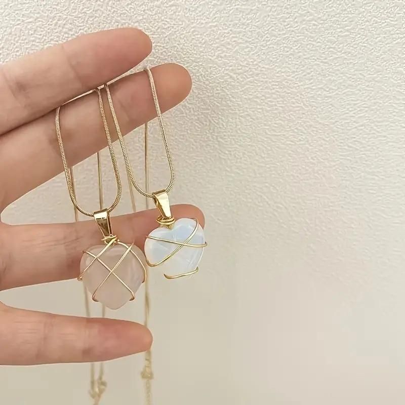 Heart-shaped pendant with rose gold wire wrapping on a soft pink fabric background