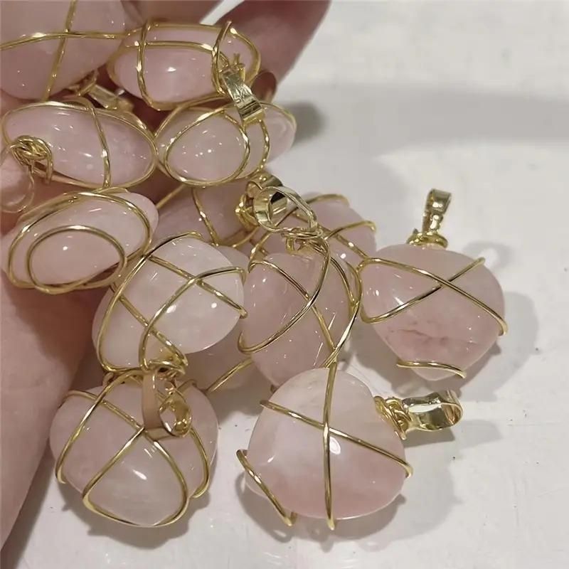 Heart-shaped pendant with rose gold wire wrapping on a soft pink fabric background